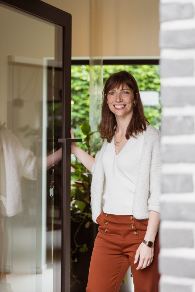 Isabelle van De Woonmakelaar opent de deur van een woning